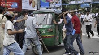 Протестующие пытаются разрушить авто рикшу, услышав вердикт суда над Гуламом Азамом (не изображен на фото), бывшим главой партии Джамаат-и-Ислами, поскольку они требуют его смертной казни в Дакке 15 июля 2013 г.