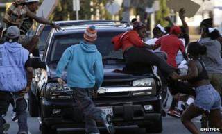 People jump on a car on Crenshaw Boulevard during a protest against the acquittal of George Zimmerman in the Trayvon Martin case in Los Angeles on 15 July 2013