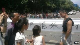 Local residents demonstrate with a banner saying "urban enforcers (chengguan) killed people" in Linwu county, central China's Hunan province, 17 July 2013