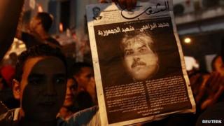 A demonstrator holds up a poster with an image of slain opposition figure Mohamed Brahmi