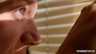 Man looking through blinds