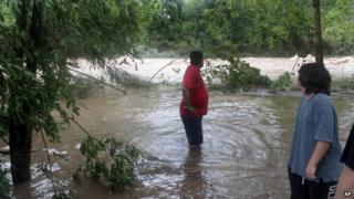 Nick Ramirez looks downstream for signs of his trailer, which was swept away by flood waters in Hollister, Missouri, on 8 August 2013