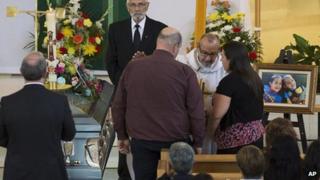 Father Maurice Frenette talks with Mandy Trecartin and Andrew Barthe at the funeral for their sons Noah and Connor Barthe, 10 August, Campbellton, New Brunswick.
