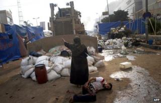 An Egyptian woman tries to stop a military bulldozer from hurting a wounded youth