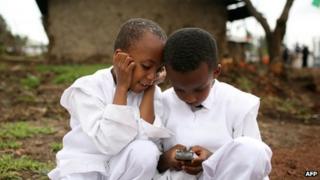 Two boys play with a mobile phone on 1 August 2008 in Debre Zeit, Ethiopia.
