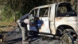 Сгоревший полицейский автомобиль осматривает офицер в Сан-Педро, к северу от Парагвая, 18 августа