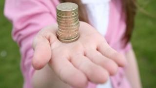 Girl holding a stack of pound coins