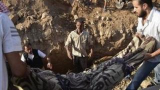 The body of a victim of a suspected chemical weapons attack is lowered into a grave in Hamoria, Damascus (21 August 2013)
