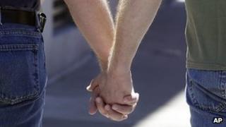 Two men hold hands while walking on Castro Street in San Francisco