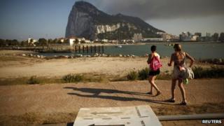 Two Spanish tourists walk past a broken traffic signal lying on the ground as they try to find the correct direction to the Spanish border to enter the British territory of Gibraltar