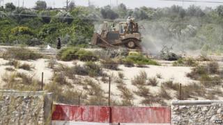 A picture taken from the southern Gaza Strip shows an Egyptian soldier standing on a bulldozer used to flatten fields near the border between Egypt and the Palestinian territory on 12 September 2013.