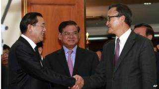 Cambodian Prime Minister Hun Sen, left, shakes hands with opposition party leader Sam Rainsy, right, after a meeting, as Sar Kheng, center, deputy prime minister, looks on at the National Assembly in Phnom Penh, Cambodia, Monday, 16 September 2013