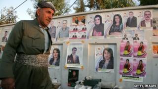 An Iraqi Kurdish man walks past electoral campaign posters in the northern Iraqi city of Irbil