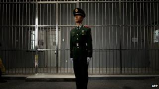 A paramilitary guard stands before the bars of a main gate to the No.1 Detention Centre during a government guided tour in Beijing on 25 October 2012