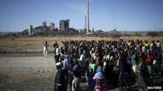 Miners chant slogans as they march past the Lonmin mine during the one-year anniversary commemorations to mark the killings of 34 striking miners by police (August 2013)