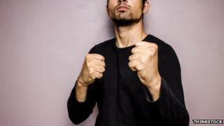 Unidentified man in black sweater with fists raised