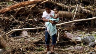 A boy holds a child in his arms while crossing a river on the mountain range of Zihuatanejo in Guerrero state on 22 September, 2013
