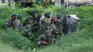Indian army soldiers gather behind a small wall during an attack by militants on an army camp at Mesar in Samba District, some 20kms south-east of Jammu on September 26, 2013