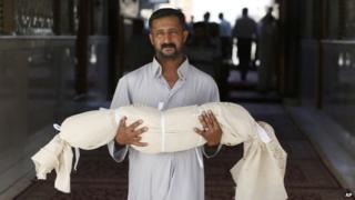 A man carries the body of his five-year-old son, who was killed in a bombing in Najaf, Iraq (14 September 2013)
