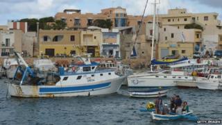 Flowers are laid in the harbour near Lampedusa to remember the 300 people who died when a boat sank there.