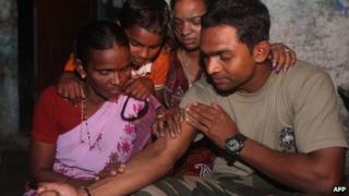 Indian police commando, Ganesh Raghunath Dhangade (R), shows a tattoo to his family in Thane district on the outskirts of Mumbai on October 16, 2013.