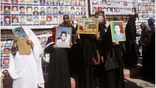 Relatives hold portraits of prisoners who died during the 1996 Abu Salim Prison massacre, as they protest outside the appeals court in Tripoli, 24 October, 2013.