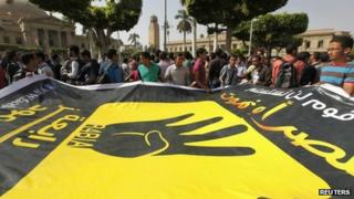 Cairo university students and members of the Muslim Brotherhood carry a banner with the four-fingered symbol of Rabaa