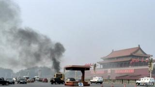 Vehicles travel along Chang'an Avenue as smoke raises in front of a portrait of late Chinese Chairman Mao Zedong at Tiananmen Square in Beijing 28 October 2013