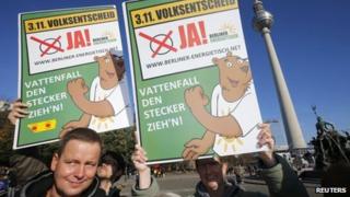 Activists hold posters which read "Vattenfall pull the plug!" as they take part in a protest urging a "yes" vote on whether the electricity grid be returned to public ownership in Berlin on Thursday