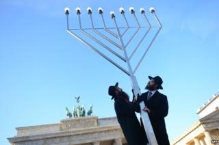 Двое еврейских мужчин с гигантской менорой перед Бранденбургскими воротами
