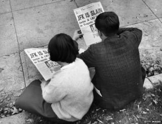Два человека в парке Лафайет в Вашингтоне читают в газетах сообщения об убийстве президента Джона Ф. Кеннеди
