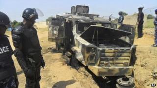 Police look down on a burned out army personal carrier following an attack by Boko Haram in Damaturu, Nigeria