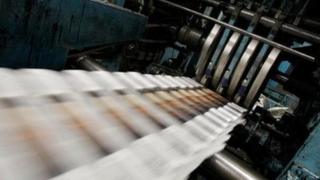 Newspapers roll off a printing press.