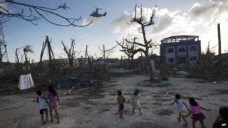 Children run towards a US military aircraft as it arrives to distribute aid in Guiuan, Philippines on 14 November 2013