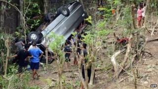 People look at the wreckage of a tourist bus one day after it plunged into a ravine in Uluwatu on Indonesia's resort island of Bali on 19 November 2013