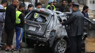 Iraqis inspect a damage car after a bomb attack in Baghdad's Karrada district (20 November 2013)