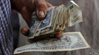 A farmer holds a wad of Cuban money