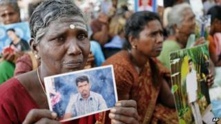 Sri Lankan ethnic Tamil women cry holding portraits of their missing relatives during a protest in Jaffna, Sri Lanka, Friday, Nov. 15, 2013