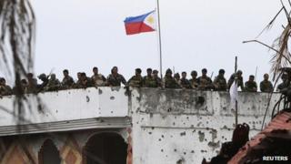 Soldiers stand next to the Philippine national flag on a mosque formerly occupied by Muslim rebels of Moro National Liberation Front (MNLF) in Zamboanga city, southern Philippines, 28 Sept