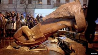 People surround a statue of Soviet state founder Vladimir Lenin, which was toppled by protesters during a rally organized by supporters of EU integration in Kiev, December 8, 2013