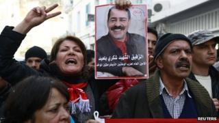 A member of the main labour union body UGTT holds a poster of assassinated secular opposition leader Chokri Belaid during a protest calling for the government led by the Islamist Ennahda party to step down, in Tunis December 4, 2013