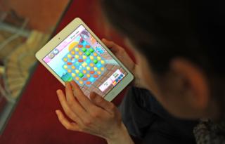 Женщина играет Candy Crush Saga на iPad