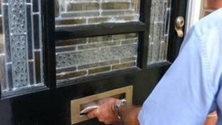 Postman putting letters through a letter box