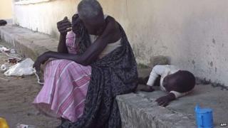 A South Sudanese woman sits with a child sits at the main hospital in Bor, after its recapture by government forces, 25 December