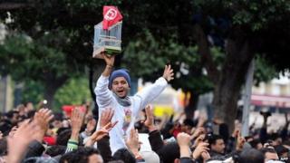 A Tunisian demonstrator holds a cage and the national country flag, during a rally on 14 January 2011 outside the Interior ministry in Tunis, Tunisia