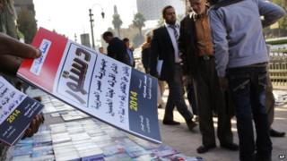 An Egyptian distributes copies of the new constitution on a street in Cairo, Egypt