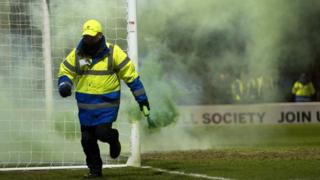 A steward removes a flare at Fir Park
