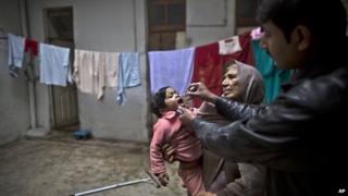 A Pakistani health worker, right, gives a polio vaccine to a child held by her grandmother at their home in Rawalpindi, Pakistan, Monday, Jan. 20, 2014.