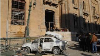 Egyptian men stand next to the wreckage of a car outside the Museum of Islamic Art in Cairo, following a bomb explosion that struck the nearby police headquarters.