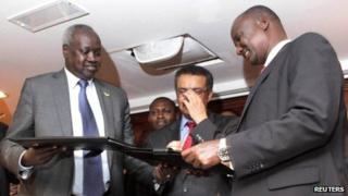 South Sudan's leader of the government's delegation Nhial Deng Nhial (L) exchanges a signed ceasefire agreement with the head of the rebel delegation General Taban Deng Gai (R)